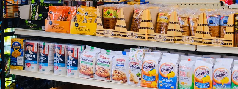Supermarket shelves stocked with brightly colored packaged snack foods and crackers