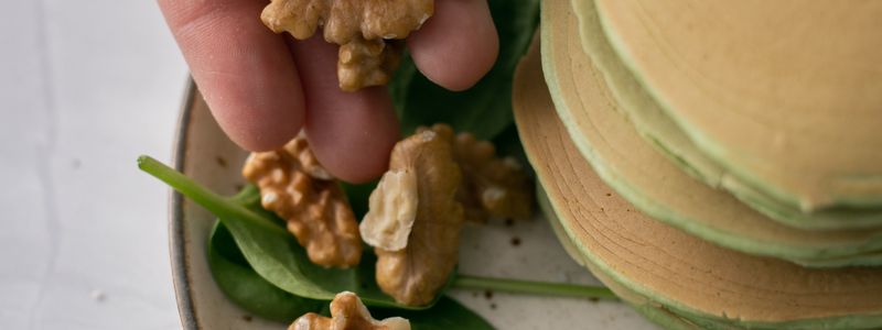 A fresh spinach salad topped with walnuts on a plate