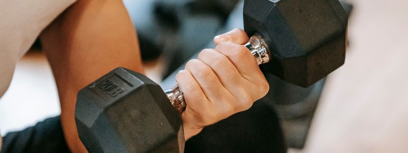 A close-up of a hand gripping the handle of a hex dumbbell