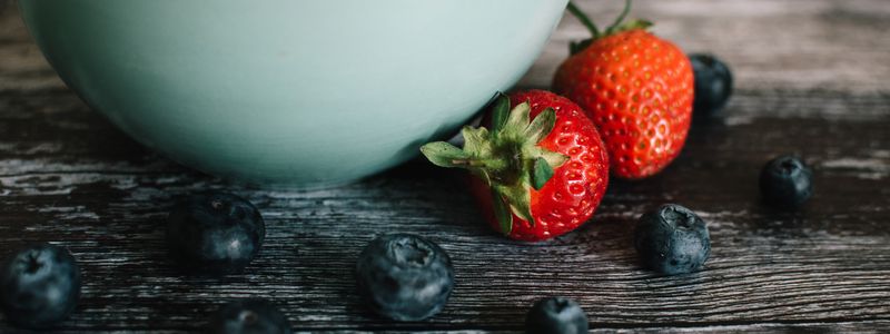 Strawberries and blueberries beside a ceramic bowl