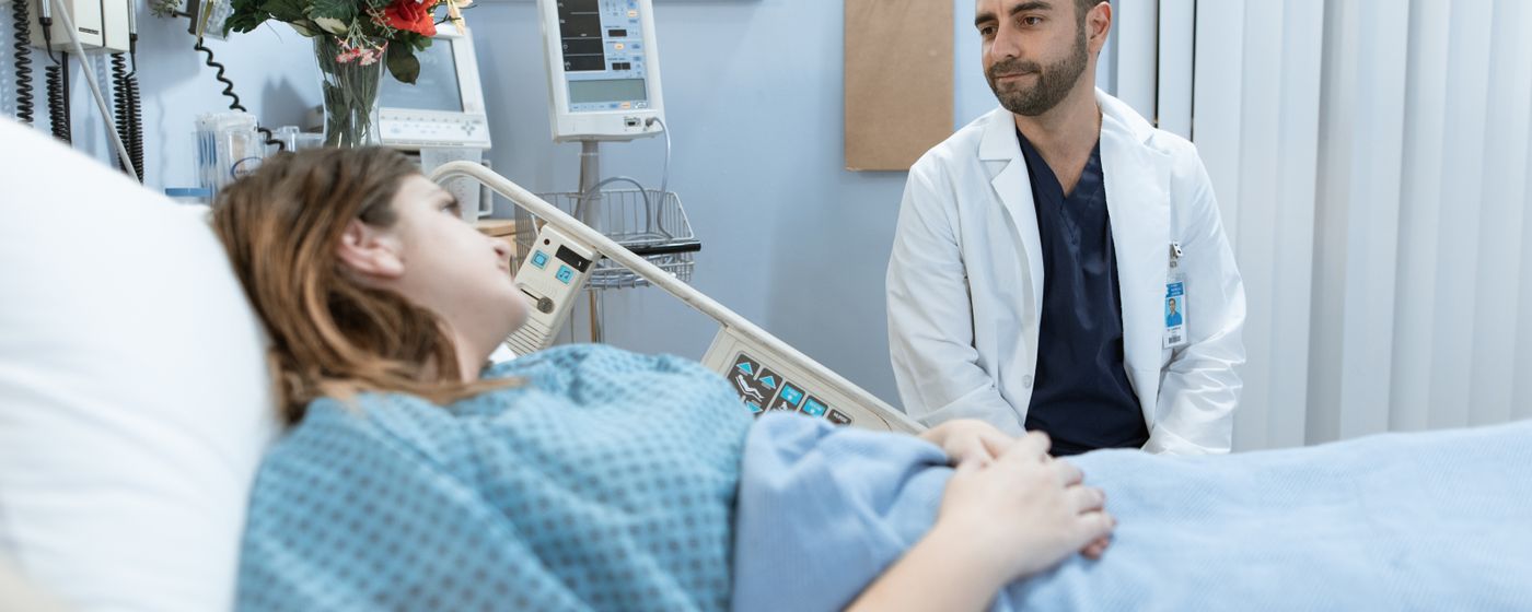 A doctor comforts a patient in a hospital room