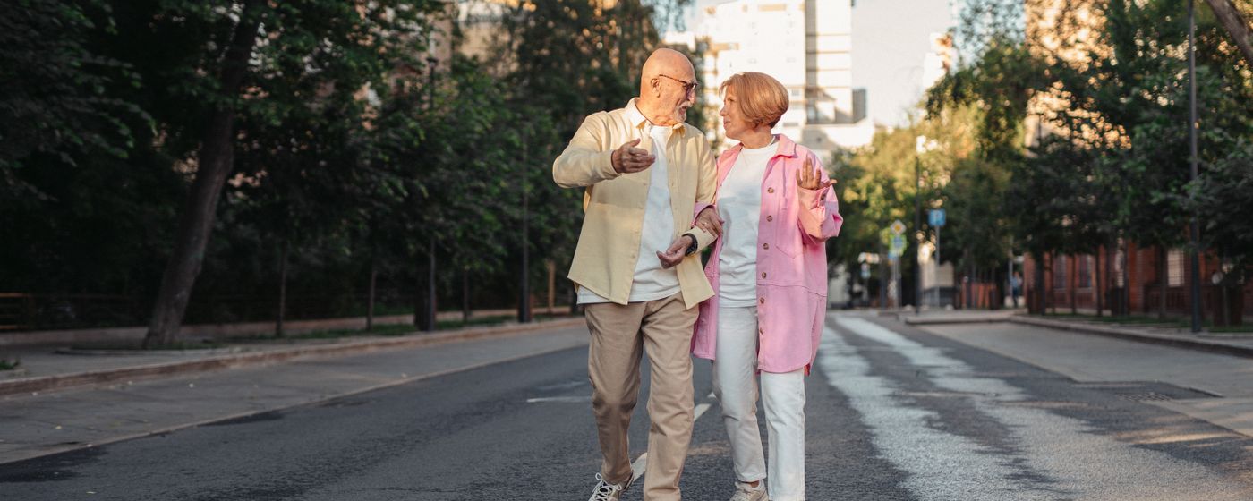 Happy elderly couple strolling down a sunny city street