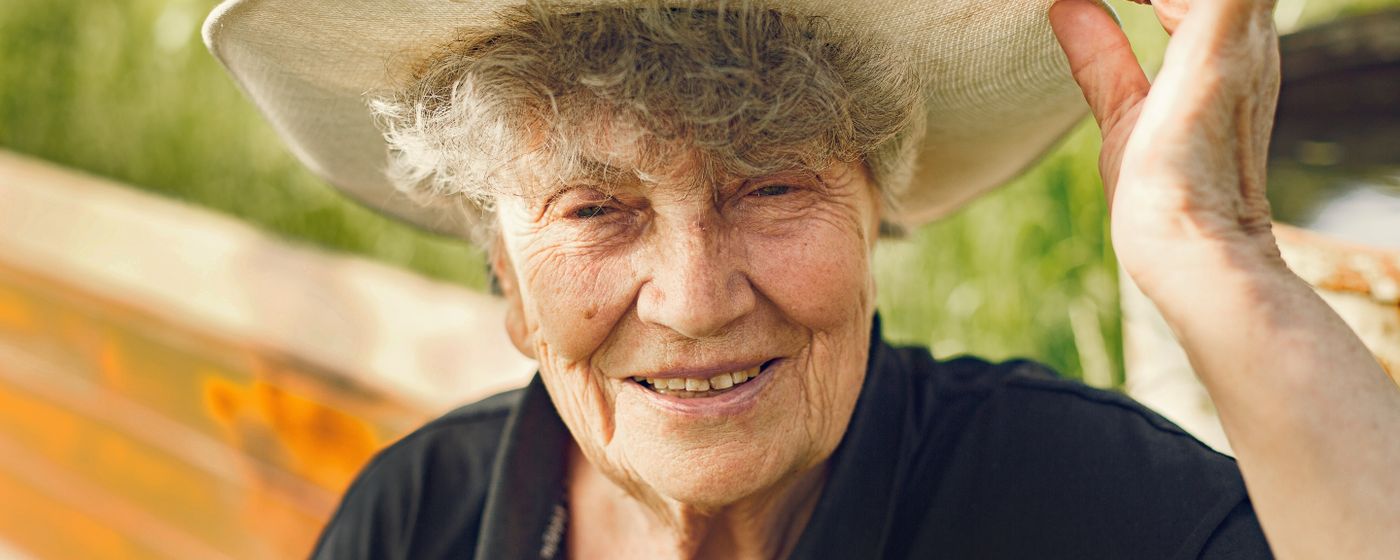 Portrait of an elderly woman wearing a sun hat, smiling under the sun