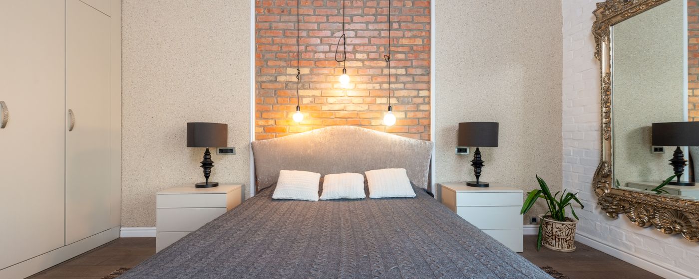 A dimly lit bedroom with warm bedside lamps and a made bed