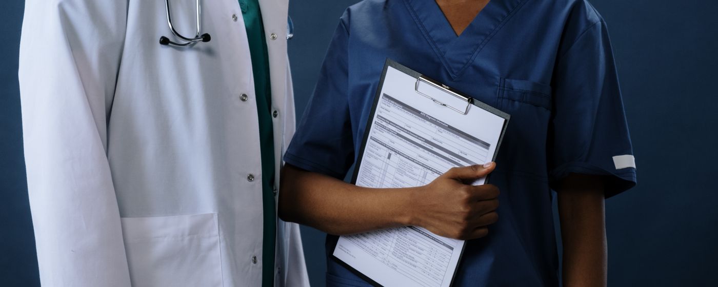 A clinician in scrubs holding a clipboard with a printed form