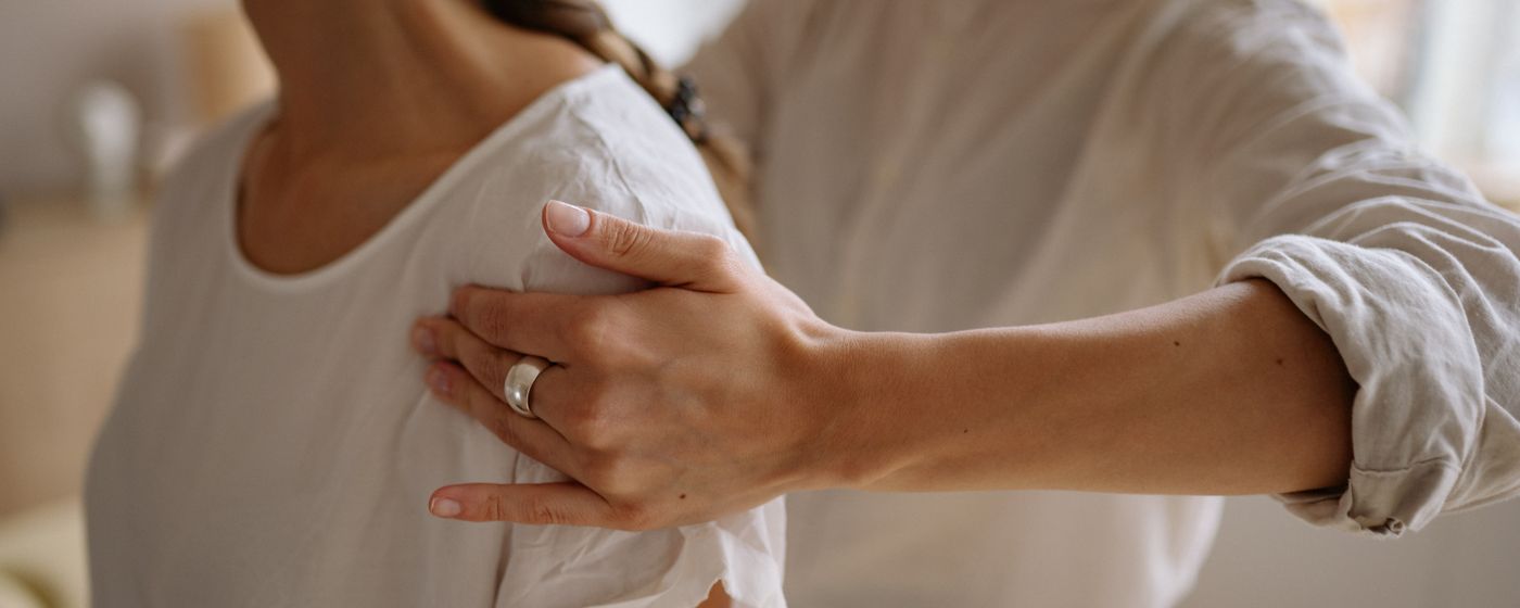 A hand resting on a person's shoulder during a physiotherapy assessment