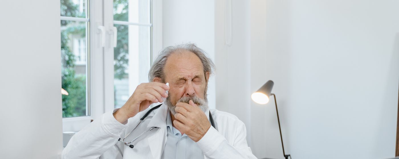 An older man with his eyes closed holding his glasses up to his face