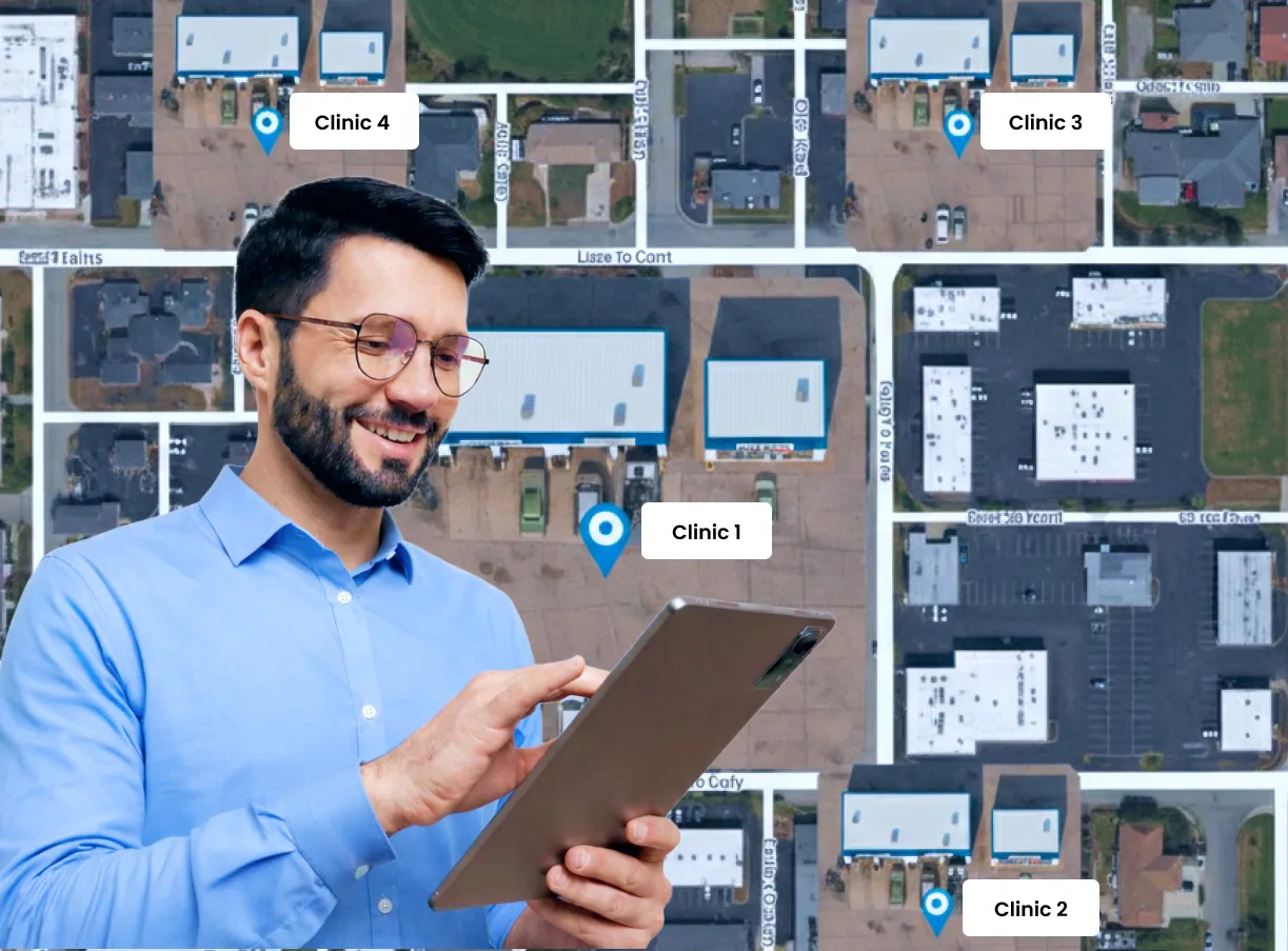 Smiling man using a tablet overlayed on an aerial map with locations marked for Clinic 1, Clinic 2, Clinic 3, and Clinic 4.
