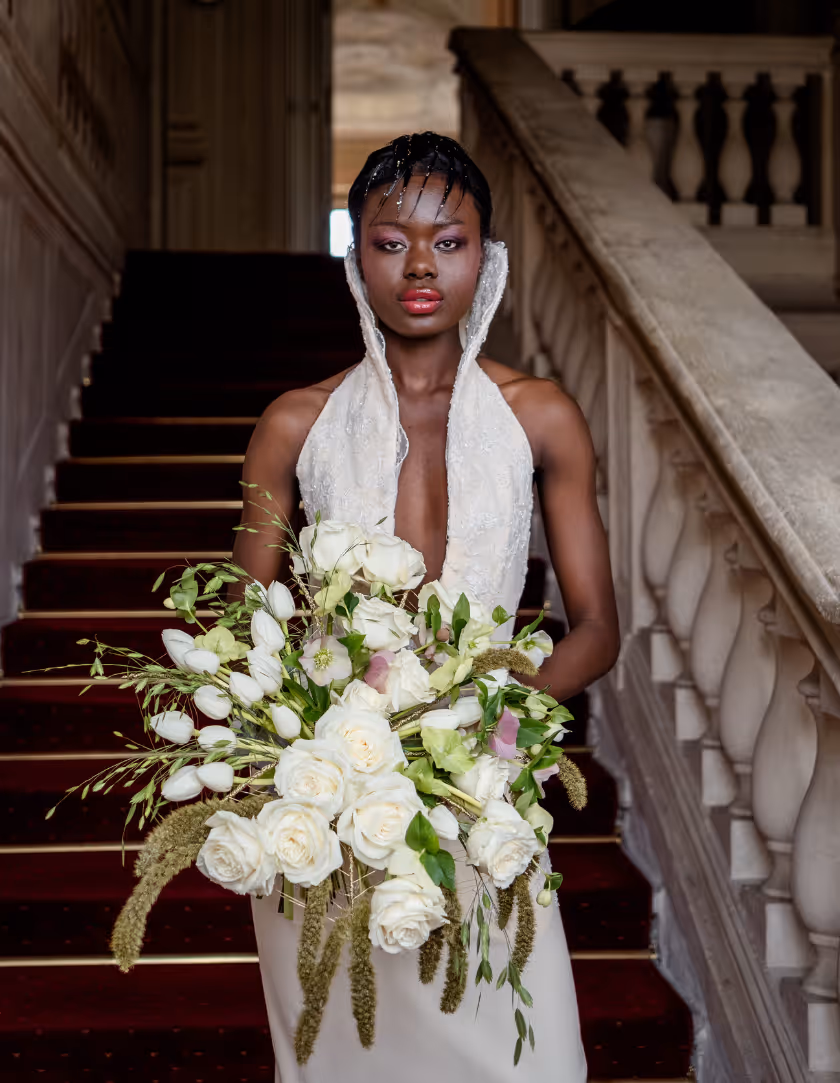 Sposa che cammina lungo una scala con bouquet bianco
