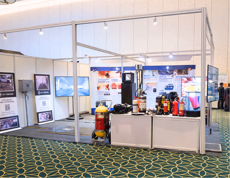 Exhibition booth displaying various fire suppression equipment including fire extinguishers, promotional banners, and screens.