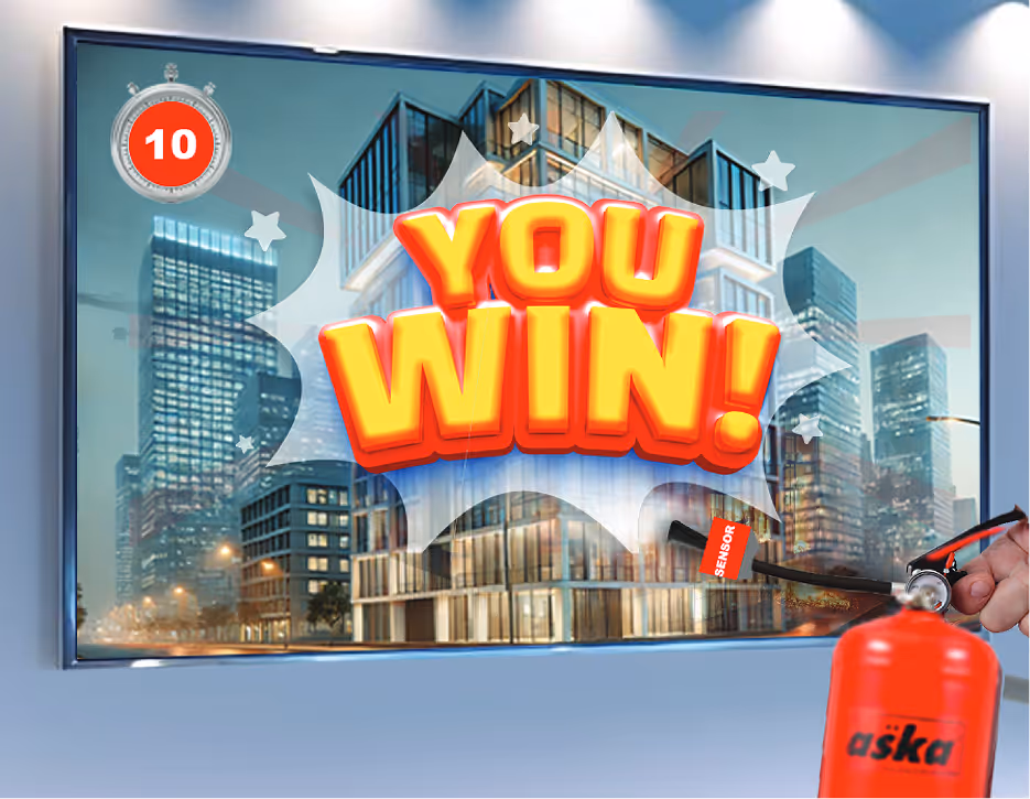 Screen showing a cityscape with a timer reading 10 seconds and bold text saying 'YOU WIN!', with a hand holding a red Aska fire extinguisher pointed at the screen.