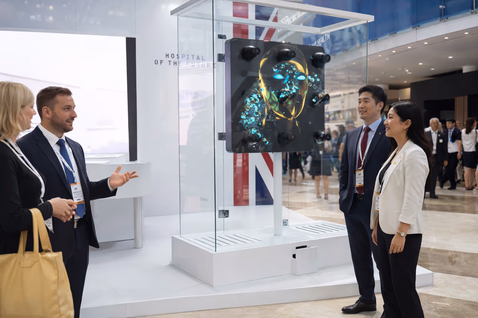 Four professionals observing a futuristic digital hologram display of a glowing human head inside a glass case at an exhibition.