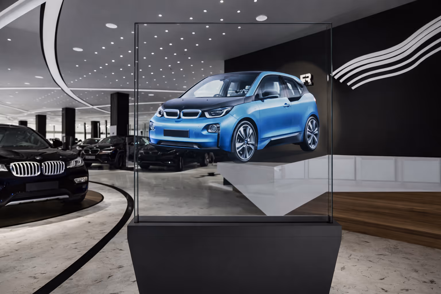 Blue compact electric car displayed as a hologram inside a modern showroom with other black vehicles.