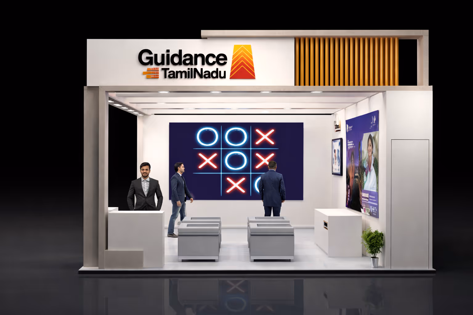 A modern exhibition booth for Guidance Tamil Nadu with three men inside, a large tic-tac-toe game displayed on the back wall, and promotional posters on the side wall.
