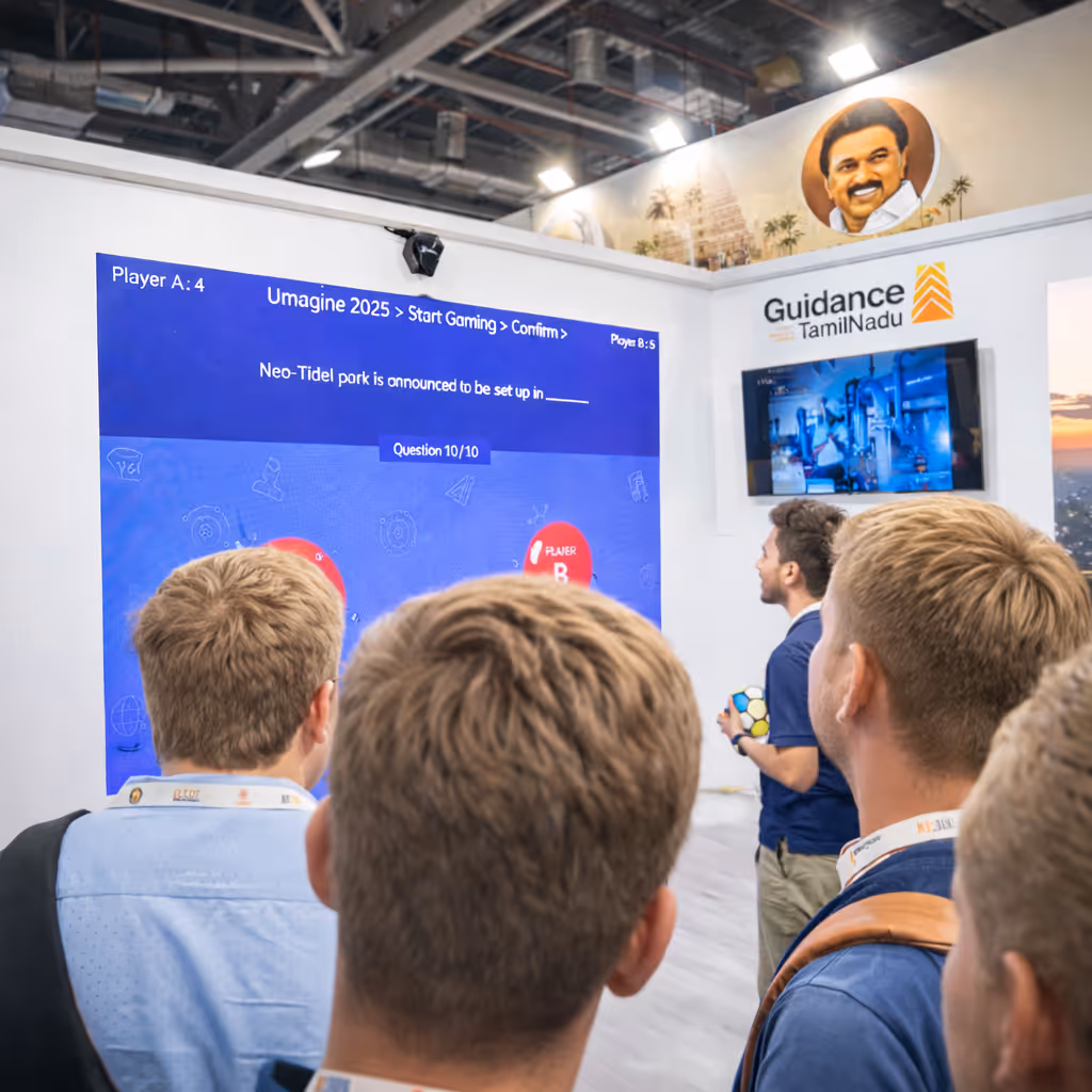 Group of people watching a large screen displaying a quiz game question at a Guidance Tamil Nadu booth in an indoor event.
