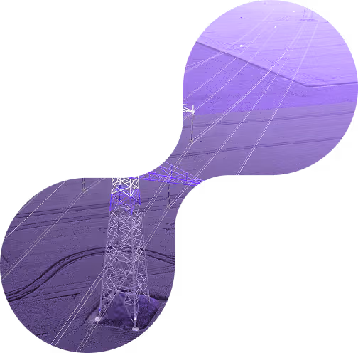 High-voltage power lines supported by metal lattice towers stretching over flat agricultural land under a purple-tinted sky.