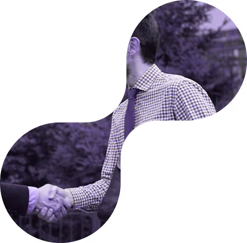 Two people shaking hands outdoors, one wearing a checkered shirt and tie.