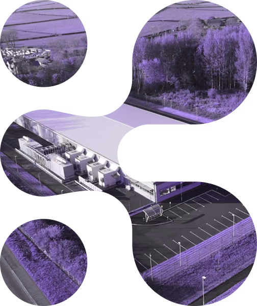 Aerial view of an industrial building with parking lot surrounded by trees and roads.