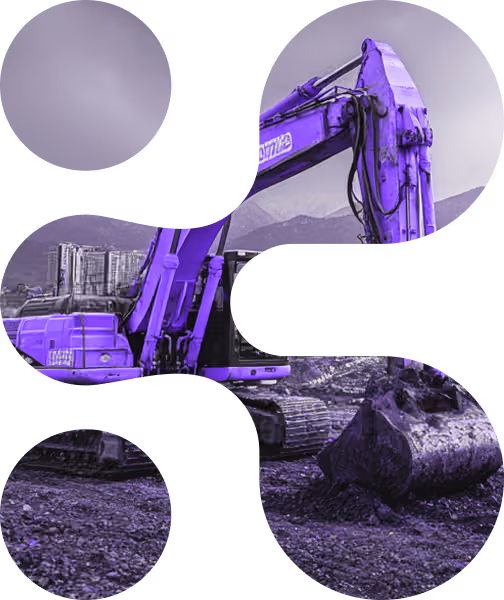 Purple-tinted excavator at a construction site with mountains and buildings in the background.