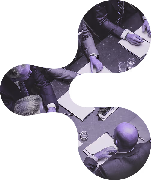 Business professionals in suits engaged in a meeting around a table with notebooks and glasses of water.