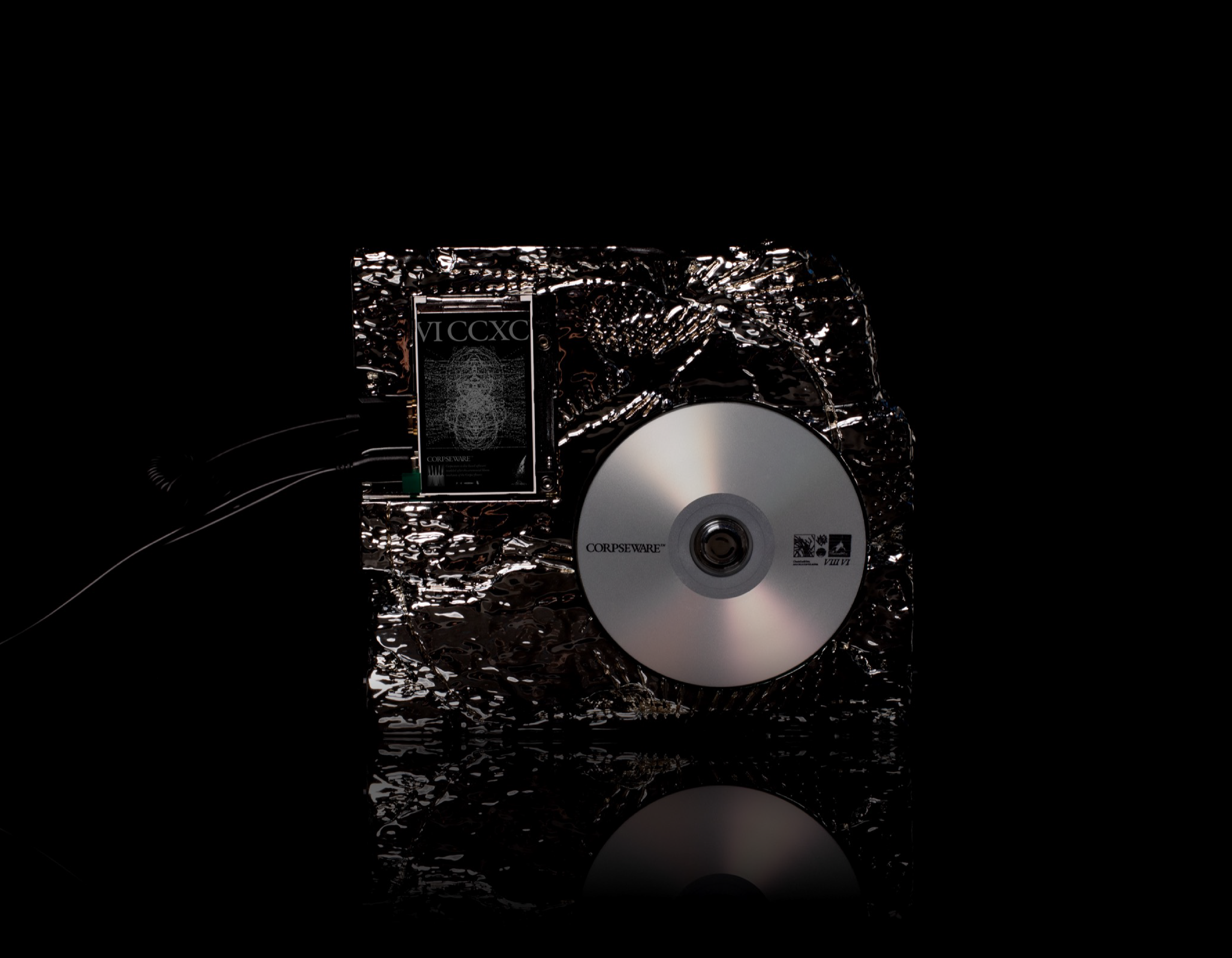 Disque avec texte Corpseware posé sur une surface métallique texturée noire.