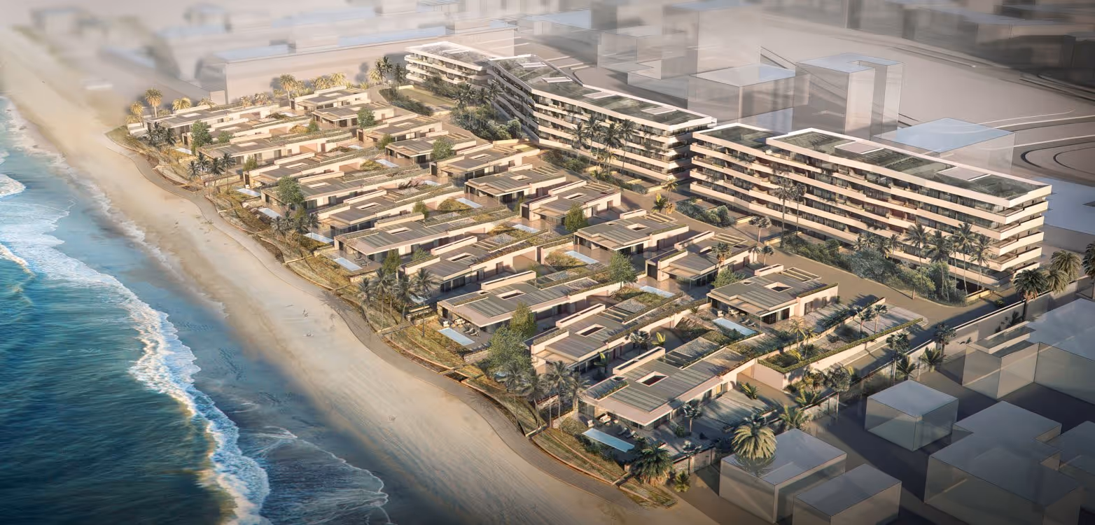 Aerial view of a beachfront resort development with low-rise villas along the shore.