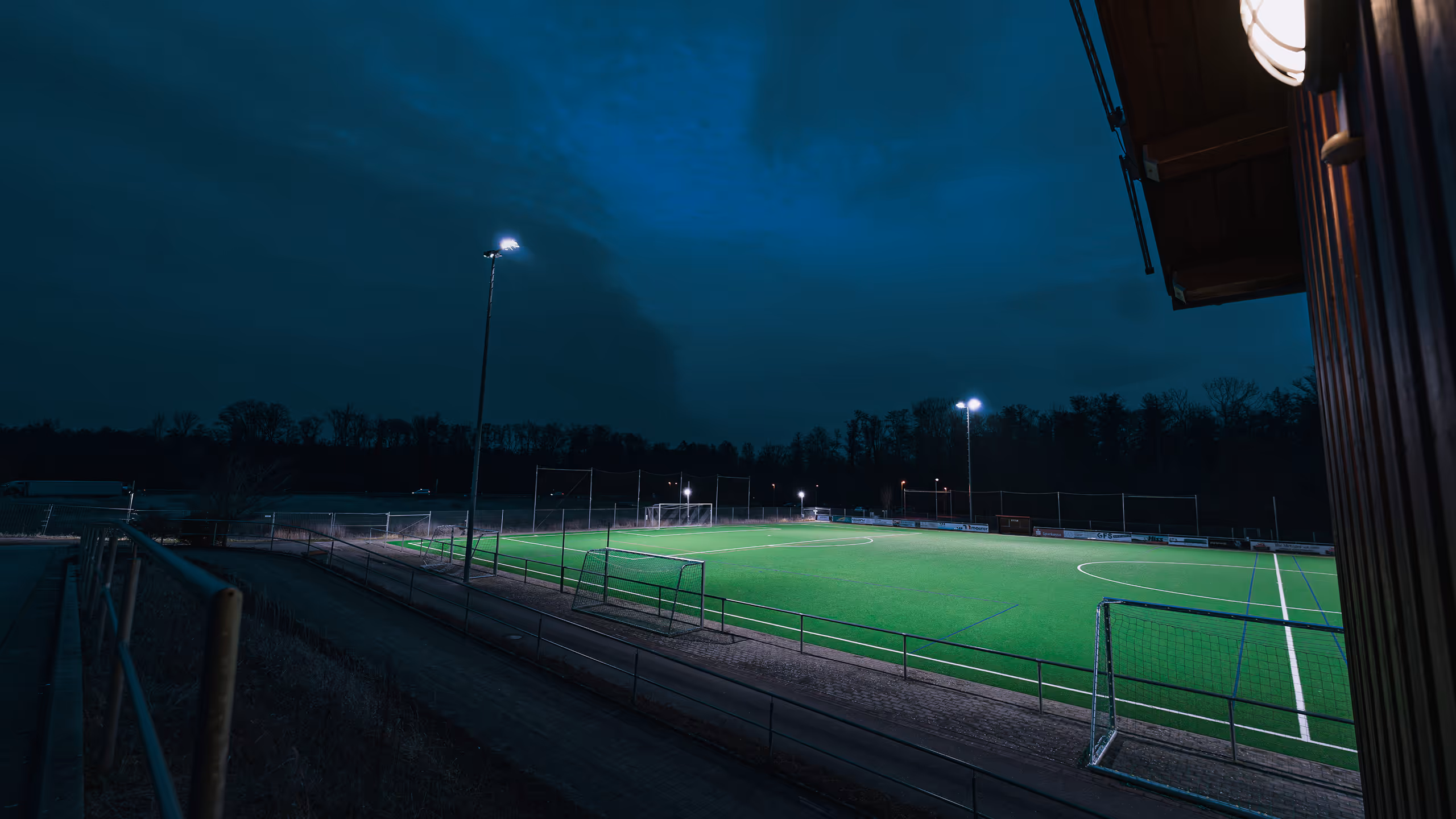 LED-Flutlichtanlage auf einem Fußballplatz einer Sportanlage bei Abendbetrieb mit gleichmäßiger Ausleuchtung