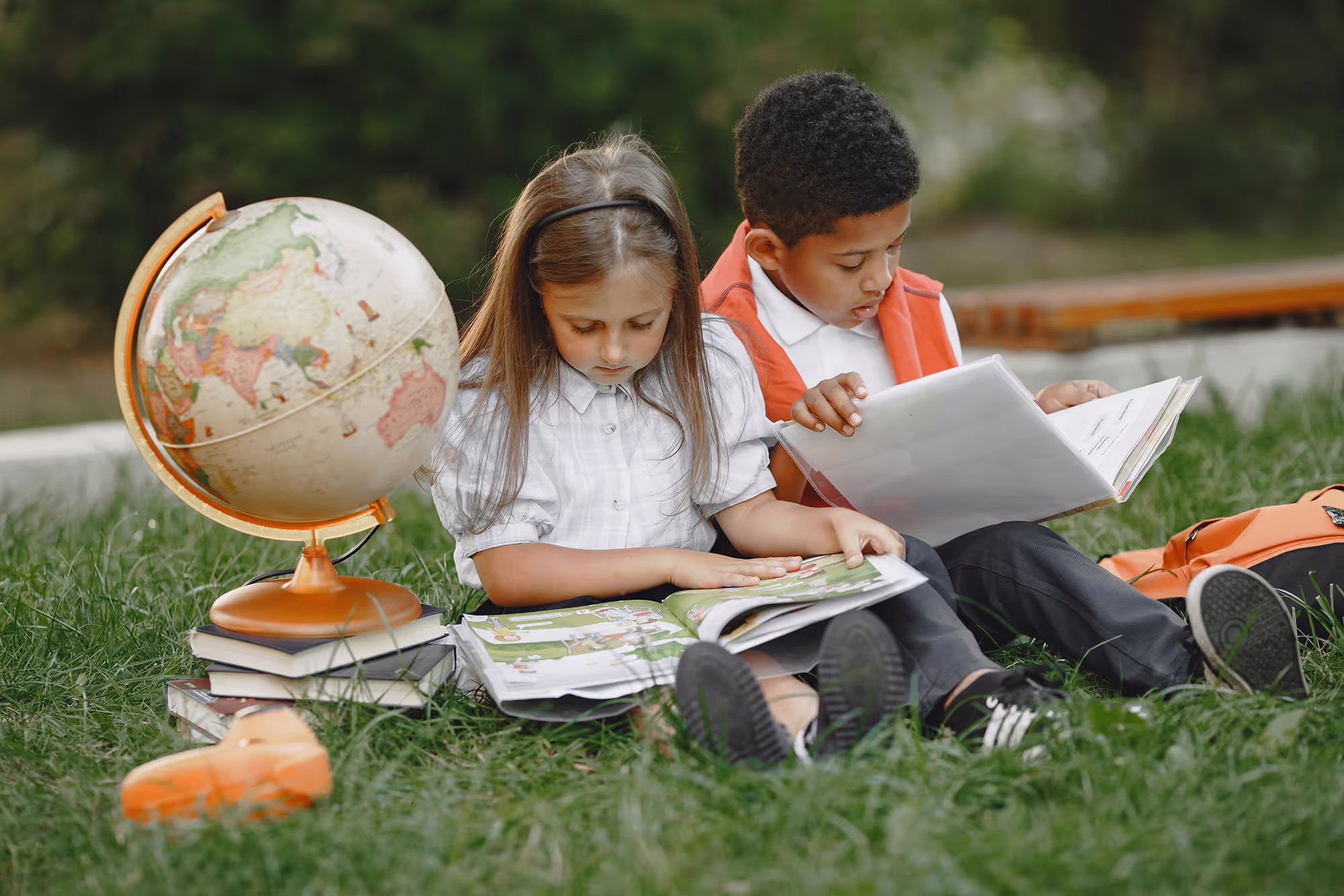 Children are sitting on the grass, reading a book together