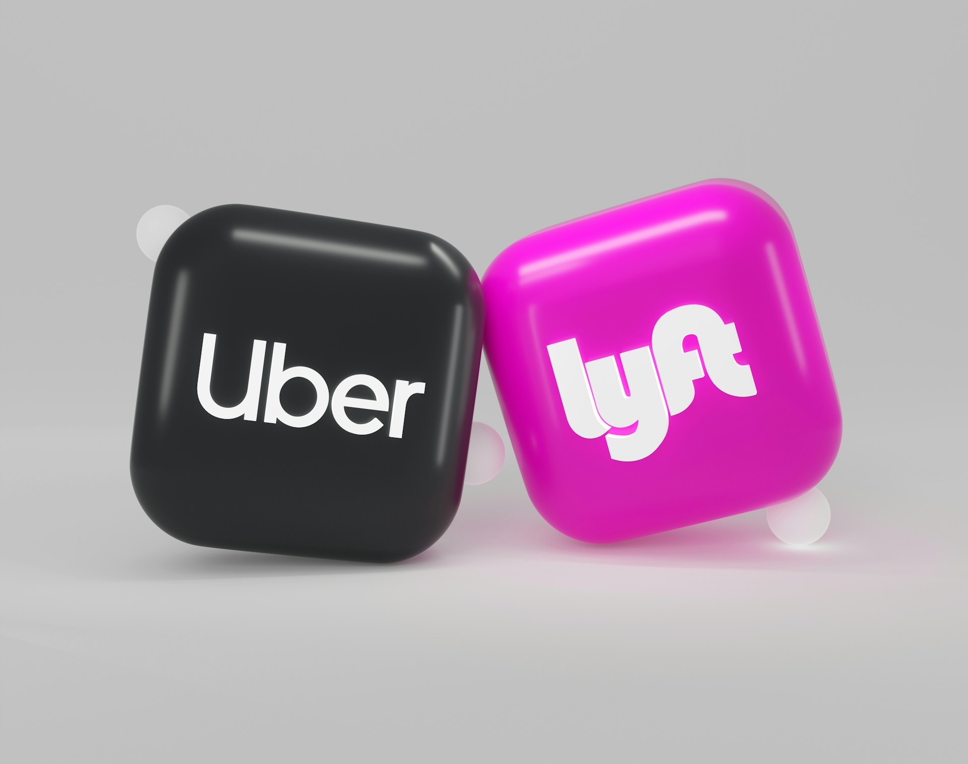 Three-dimensional Uber and Lyft app icons side by side.