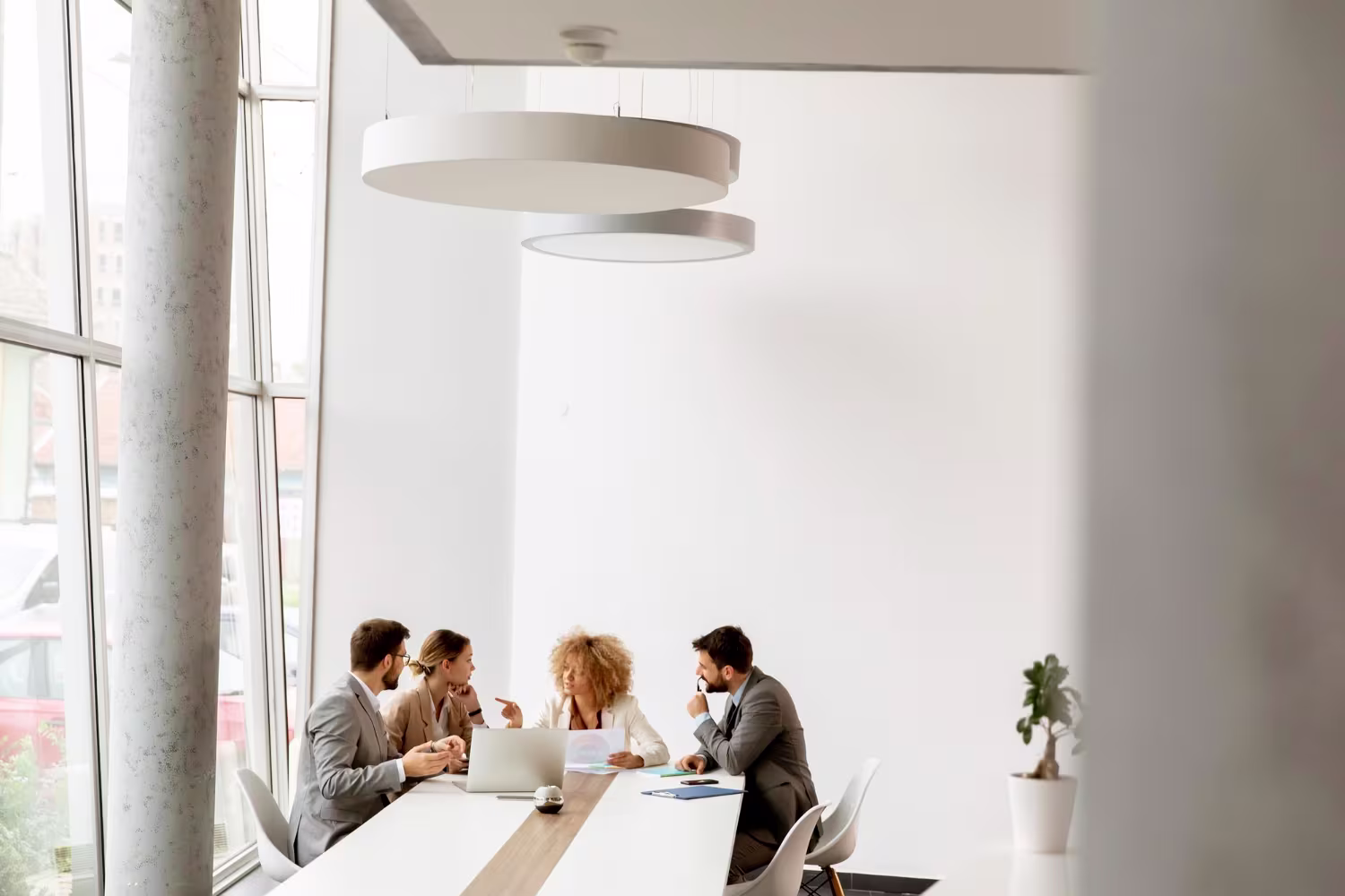 Executive team in a formal boardroom discussion with Oracle NetSuite on a laptop