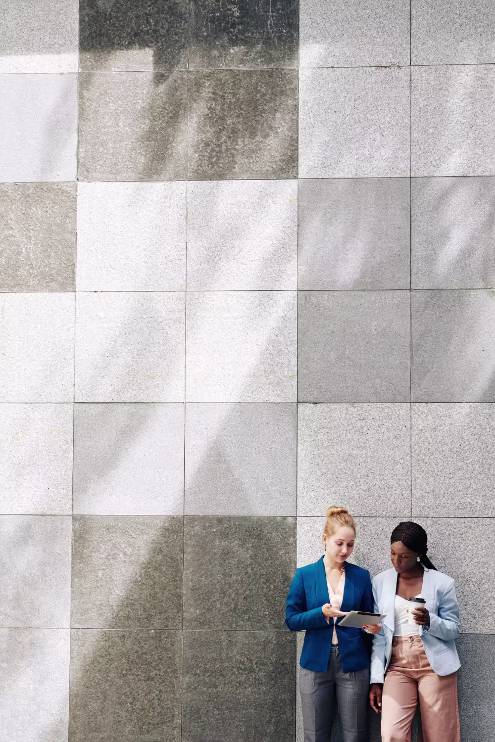 Two business professionals reviewing ERP data on tablets in a modern outdoor setting