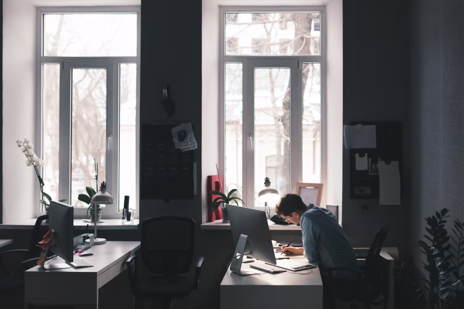Developer or ERP consultant working late at a desk with dual monitors in a dark office