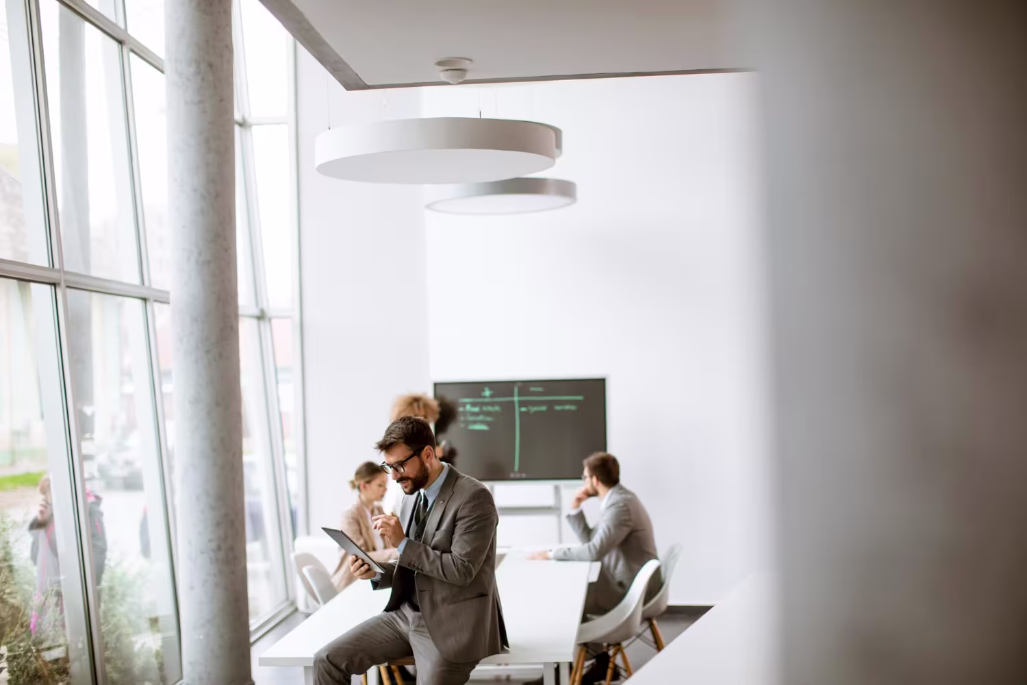 ERP consultant reviewing business data on a tablet in a modern bright meeting room