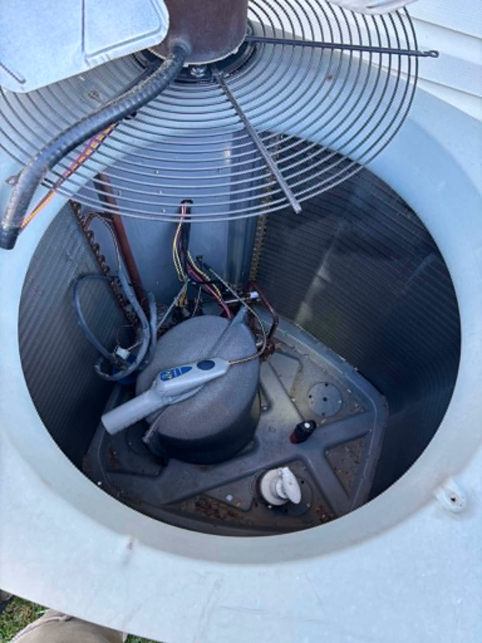 Inside of an outdoor air conditioning unit showing the compressor and wiring components.