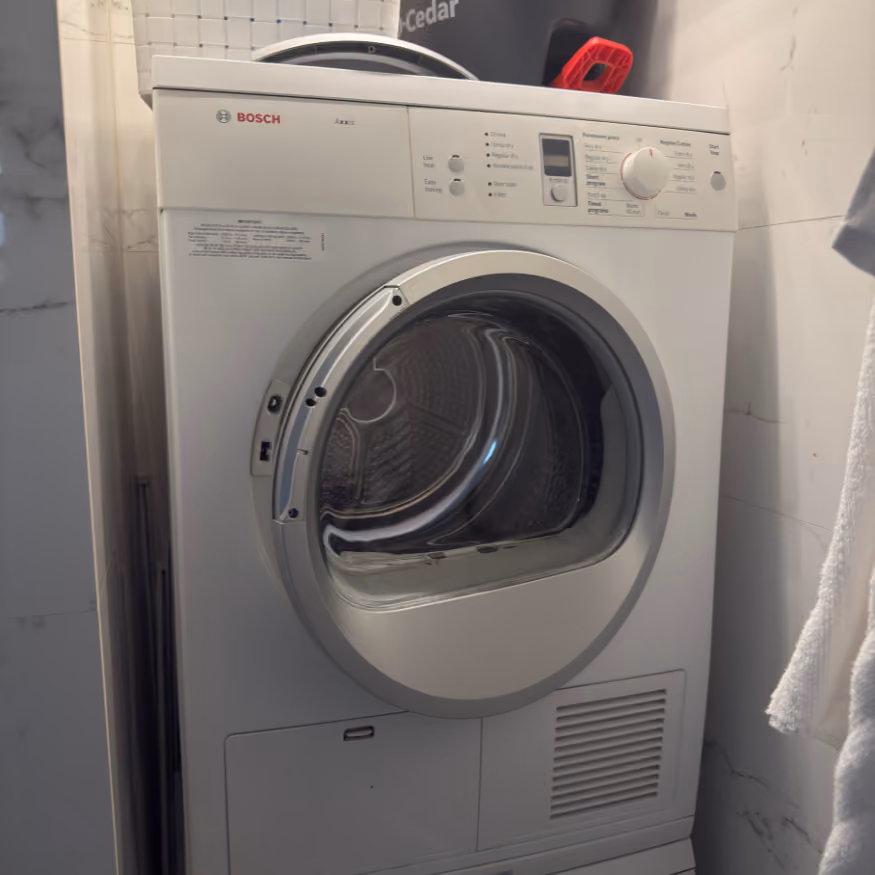 White Bosch front-load dryer with control panel and round door in a tiled laundry room.