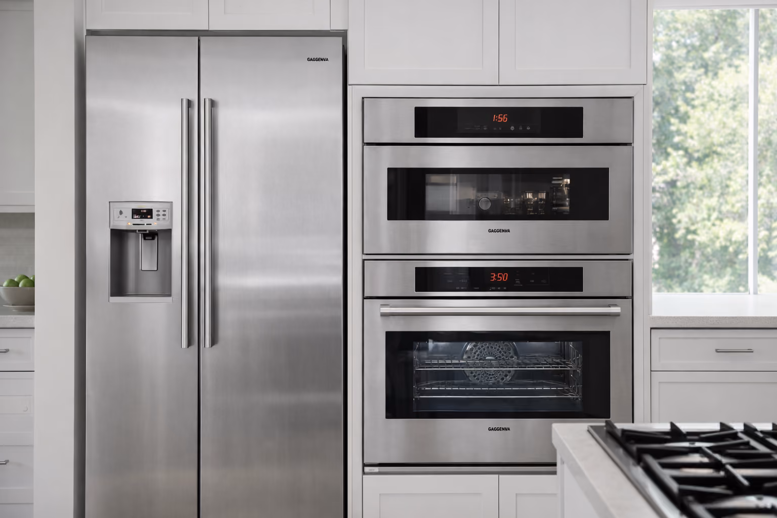 Stainless steel side-by-side refrigerator beside two built-in ovens.