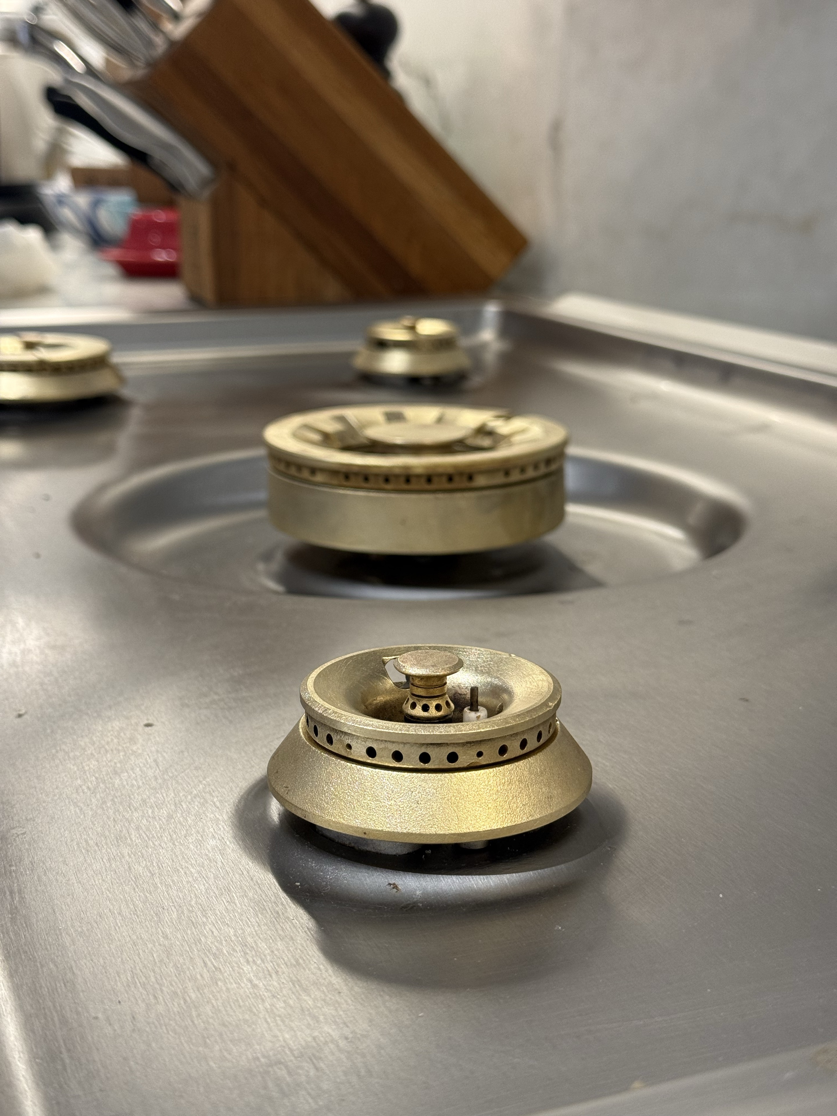 Close view of a brighter brass burner assembly installed on the Gaggenau cooktop