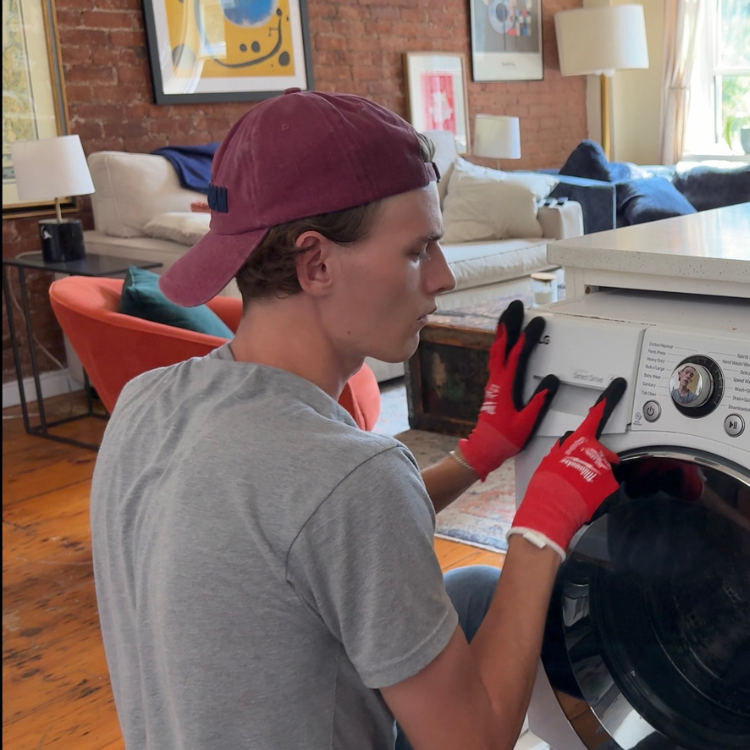 Technician pointing to the detergent drawer on a front-loading washer.