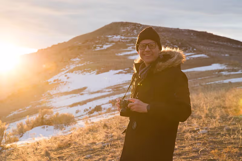 Een afbeelding van een man die in de winter in een open veld staat.