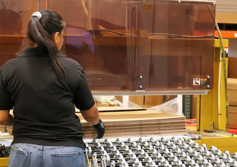 En kvinna arbetar med Packsize-lösningar i en lagermiljö.