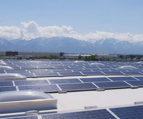 Ein Foto von einer Reihe von Solarmodulen, die im Sonnenschein aufgeladen werden, mit Blick auf die Berge im Hintergrund.