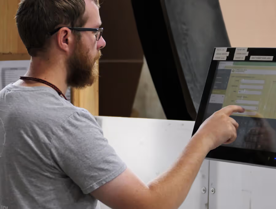 A man using the touchscreen on a Packsize, right-sized box packaging machine.