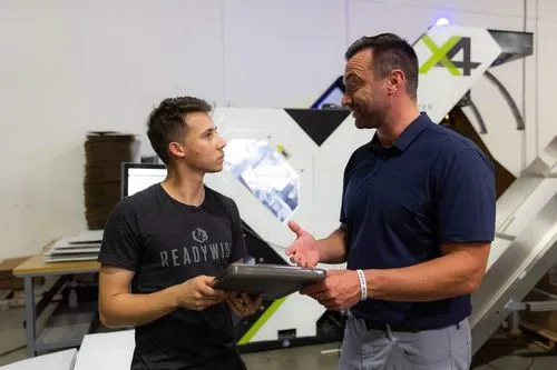 A photo of a ReadyWise employee working with a Packsize representative in front of a Packsize X4 automated packaging solution.