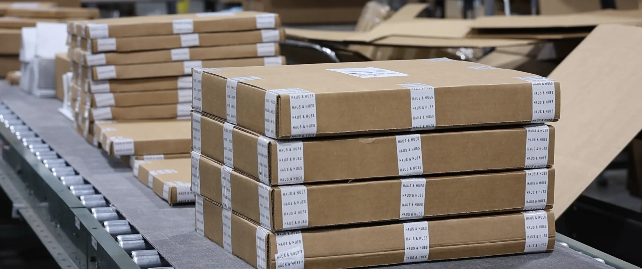 Pudełka o dopasowanych wymiarach Packsize na przenośniku w magazynie Haus and Hues.