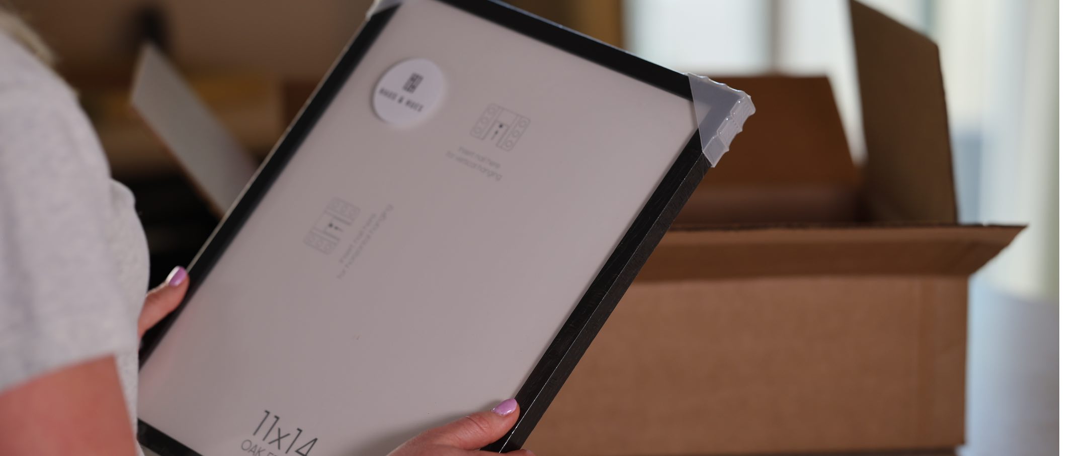 Rozpakowana ramka na zdjęcia Haus and Hues. W tle znajduje się pudełko Packsize o dopasowanym rozmiarze.