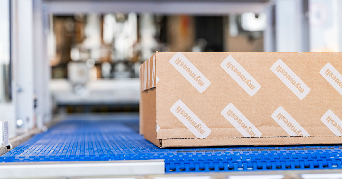 mymuesli branded shipping box on an automated packaging machine conveyor