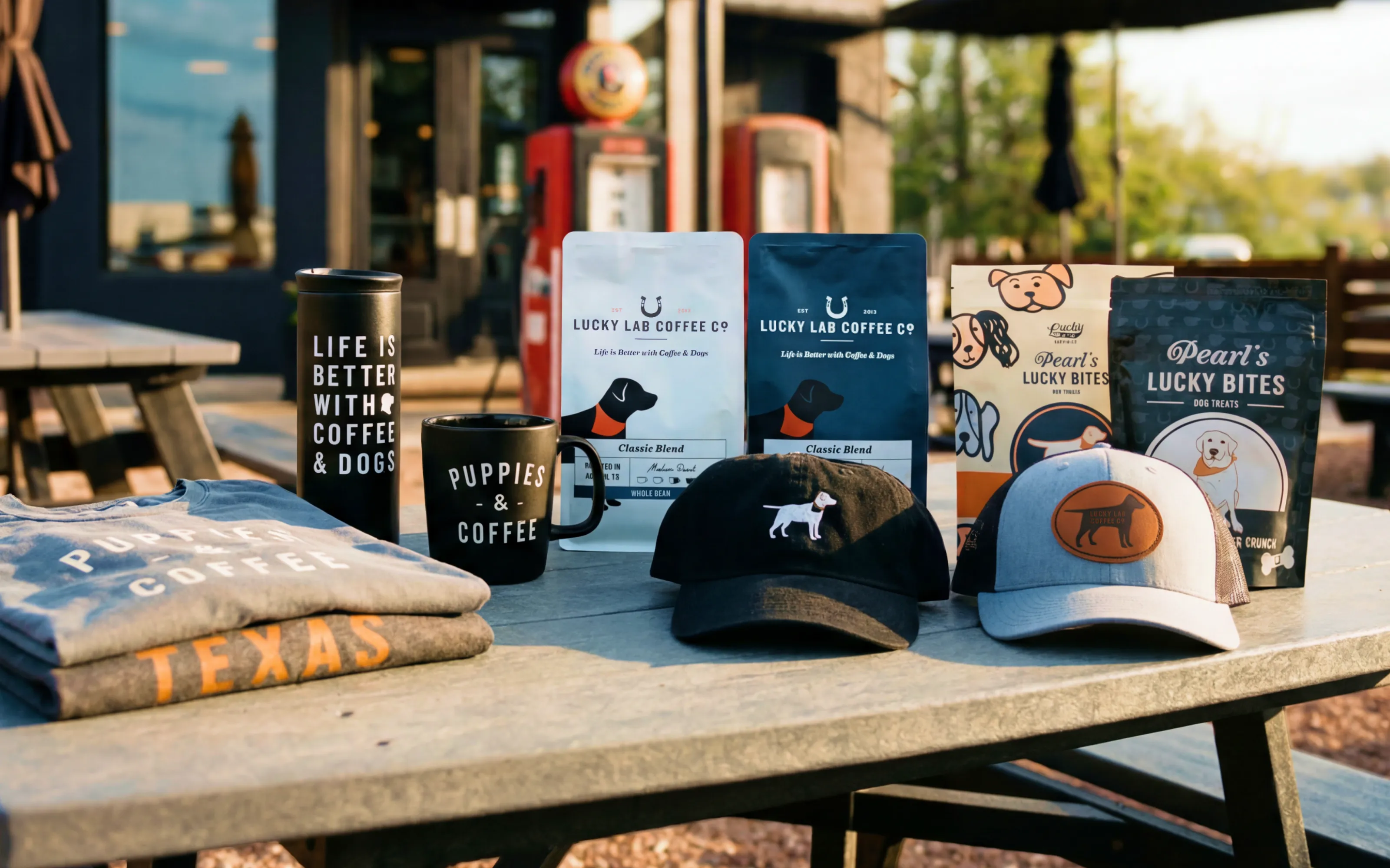 Table with coffee, mugs, apparel, caps, and dog treats showcasing Puppy and Coffee and Lucky Lab brands.