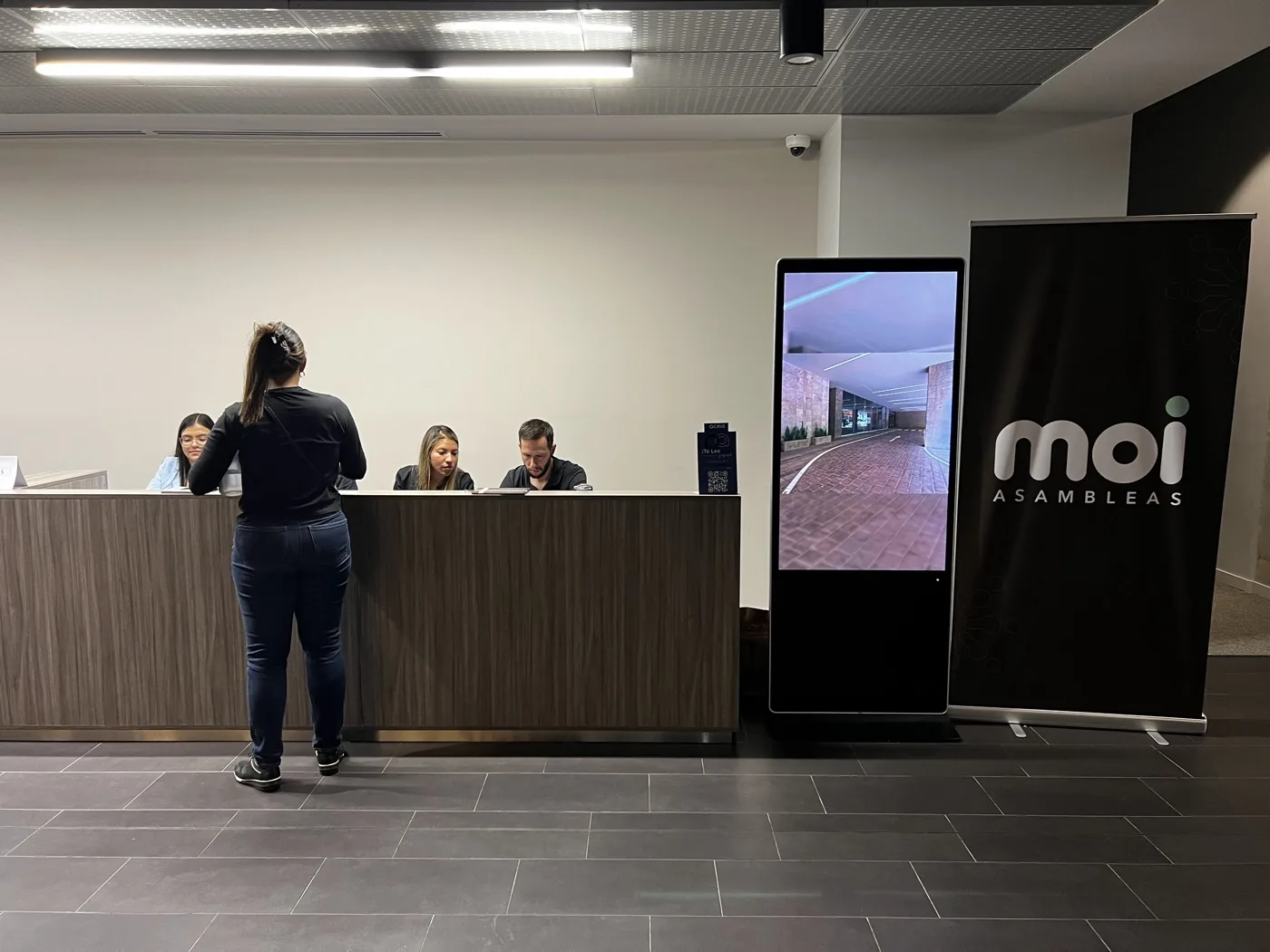 Mesa de registro de MOI Asambleas con personal en sitio, tótem digital y banner de MOI