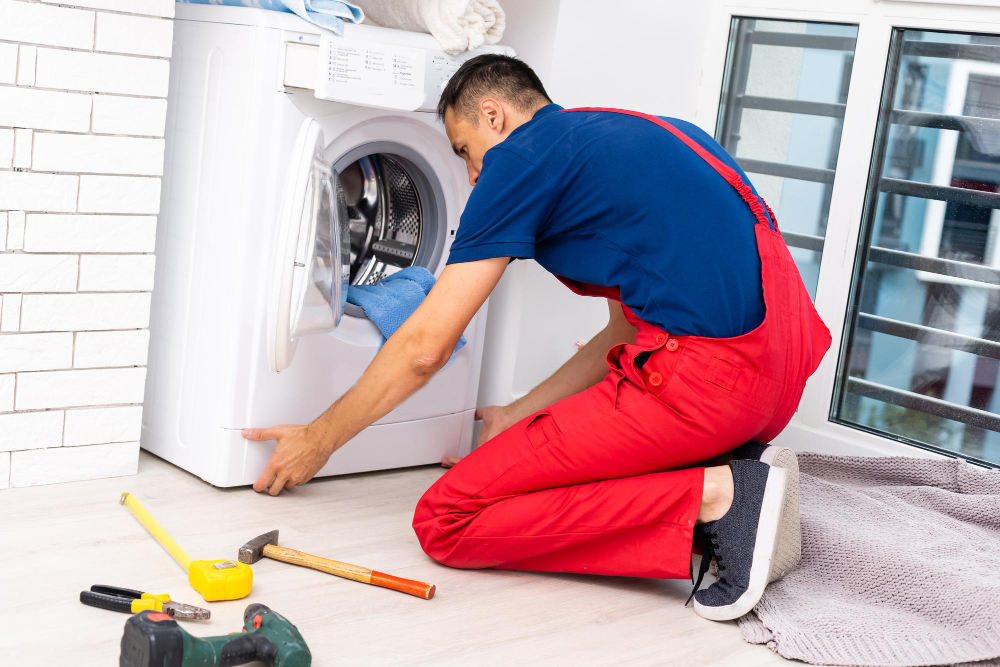 `Technician repairing a front-load washing machine`