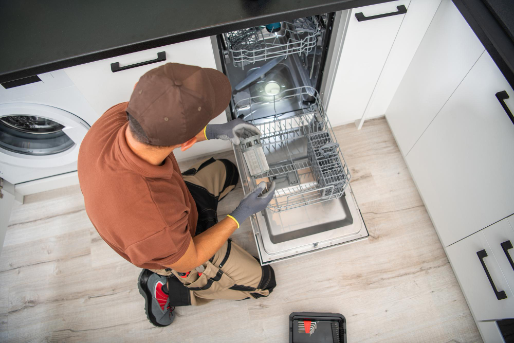 `Technician repairing a dishwasher in a kitchen`